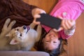 Happy young kid taking a selfie with her husky dog puppy