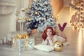 Young lady with curlu hair gifts by the fireplace near the Christmas tree. New year concept Royalty Free Stock Photo