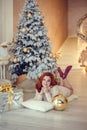 young lady with curlu hair gifts by the fireplace near the Christmas tree. New year concept Royalty Free Stock Photo