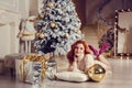 young lady with curlu hair gifts by the fireplace near the Christmas tree. New year concept Royalty Free Stock Photo