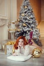 Young lady with curlu hair gifts by the fireplace near the Christmas tree. New year concept Royalty Free Stock Photo