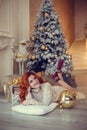 young lady with curlu hair gifts by the fireplace near the Christmas tree. New year concept Royalty Free Stock Photo