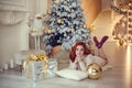 young lady with curlu hair gifts by the fireplace near the Christmas tree. New year concept Royalty Free Stock Photo