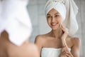 Happy young lady doing morning skincare routine after shower.