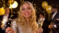 Happy young lady with glass of champagne holding sparkler, new year celebration Royalty Free Stock Photo