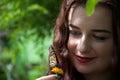 A happy lady / girl holding a flower with a butterfly sitting on it Royalty Free Stock Photo