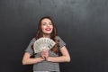 Happy young lady standing over grey wall and holding money Royalty Free Stock Photo