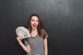 Happy young lady standing over grey wall and holding money Royalty Free Stock Photo