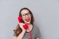 Happy young lady standing over grey wall talking by phone. Royalty Free Stock Photo