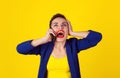 Happy young lady talking on mobile phone isolated on a yellow background Royalty Free Stock Photo