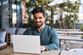 Happy young Latin business man using laptop working outdoors. Royalty Free Stock Photo