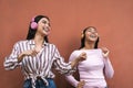 Happy young Latin women having fun dancing and listening music with headphones Royalty Free Stock Photo