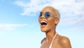 Happy young laughing woman at the beach side, wearing sunglasses, portrait of African latin American woman in sunny summer day
