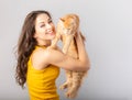 Happy young laughing woman holding on the hands her red maine coon kitten and kissing. Closeup portrait Royalty Free Stock Photo