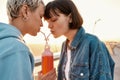 Happy young lesbian couple drinking from one glass bottle with the straw, Two women enjoying cold beverage on a summer Royalty Free Stock Photo