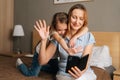 Happy young little girl embracing smiling mother greeting waving hands during online video call using mobile phone Royalty Free Stock Photo