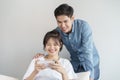 Happy young love asian couple sitting on  couch at home, looking at mobile phone, Young asian people are using smartphone Royalty Free Stock Photo