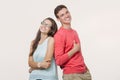 Happy young lovely couple standing back to back and smiling looking at camera on white background Royalty Free Stock Photo