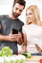 Happy young loving couple cooking together using phone Royalty Free Stock Photo