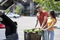 Happy young loving couple doing shopping together, standing by car Royalty Free Stock Photo