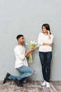 Happy young loving couple standing over grey wall. Royalty Free Stock Photo