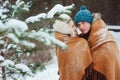 Happy young loving couple walking in snowy winter forest, covered with oversize scarf and hug Royalty Free Stock Photo