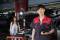 Happy young male automotive mechanic worker and a customer\'s car at the garage.