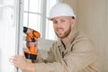 happy young male builder drilling holes in door