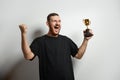 Happy young male or businessman holding his gold trophy and celebrating victory. Studio shot of man with cup as winner Royalty Free Stock Photo