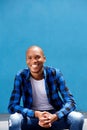 Happy young male fashion model sitting outside and smiling Royalty Free Stock Photo