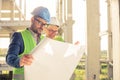 Happy young male and female architects or business partners looking at floor plans on a construction site Royalty Free Stock Photo