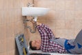 Plumber Lying On Floor Fixing Sink Royalty Free Stock Photo