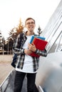 Happy young male student in casual outfit with bright smile holding folders while standing on the street Royalty Free Stock Photo