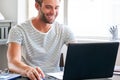 Happy young male student smiling while seated behind his laptop Royalty Free Stock Photo