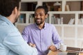 Happy young male team leader shaking hands with african colleague. Royalty Free Stock Photo