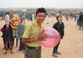 Happy young man with balloon walking in the crowd of people