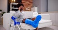 Happy Young Man With Broken Leg Sitting On Sofa Talking Royalty Free Stock Photo