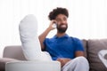 Happy Young Man With Broken Leg Talking On Mobile Phone Royalty Free Stock Photo