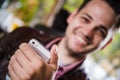 Happy young man browsing internet on smartphone sitting at outdoor cafe. Selective focus. Royalty Free Stock Photo