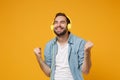 Happy young man in casual blue shirt posing isolated on yellow orange background, studio portrait. People lifestyle Royalty Free Stock Photo