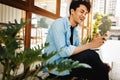 Happy Young Man in Casual wear Using Mobile Phone while Sitting in front of the Cafe