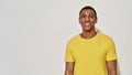 Happy young man in casual yellow t shirt smiling at camera while posing isolated over gray background Royalty Free Stock Photo