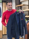 Happy young man choosing jacket in mall or clothing store. sale, shopping, fashion, style and people concept. Royalty Free Stock Photo
