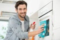 happy young man cleaning oven with rag and bottle spray Royalty Free Stock Photo