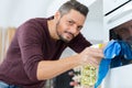 happy young man cleaning oven with rag and bottle spray Royalty Free Stock Photo