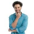 happy young man with curly hair holding hand to chin and thinking Royalty Free Stock Photo
