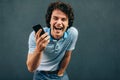 Happy young man with curly hair talking on mobile phone with his girlfriend, has joyful expression. Cheerful male laughing during