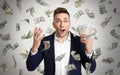 Happy young man with dollars under money rain on background Royalty Free Stock Photo