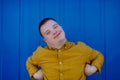 Happy young man with Down syndrome smiling and looking at camera against blue background. Royalty Free Stock Photo