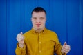 Happy young man with Down syndrome smiling and looking at camera against blue background. Royalty Free Stock Photo